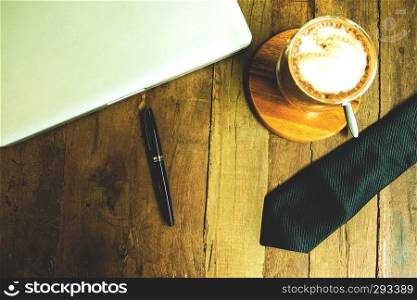 Business desktop , workspace with laptop,cup of coffee,necktie and pen on the wood table. 