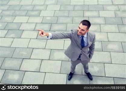 business, development and people and concept - young smiling businessman pointing finger outdoors from top