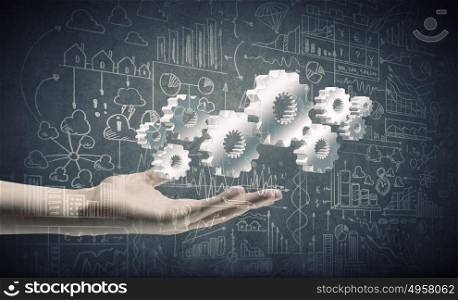 Business development. Close up of businessman hand holding gears in palm