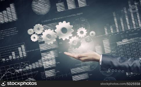 Business development. Close up of businessman hand holding gears in palm