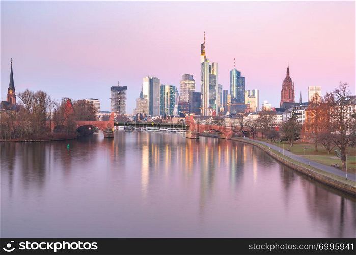 Business district with skyscrapers and mirror reflections in the river at pink sunrise, Frankfurt am Main, Germany. Frankfurt am Main in the morning, Germany
