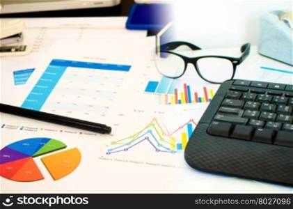 business document and keyboard and pen with business charts, graphs, statistic and documents