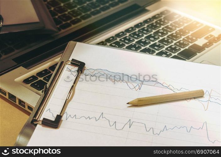 business documents graph financial on table with laptop computer and coins and diagram.