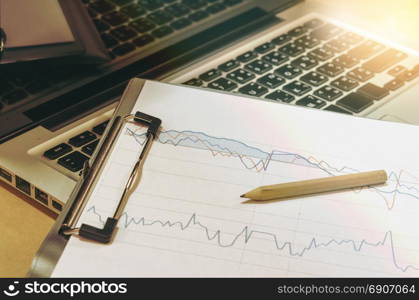 business documents graph financial on table with laptop computer and coins and diagram.