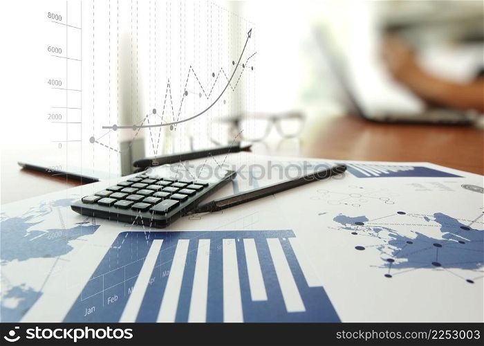business documents on office table with calculator and digital tablet and man working in the background