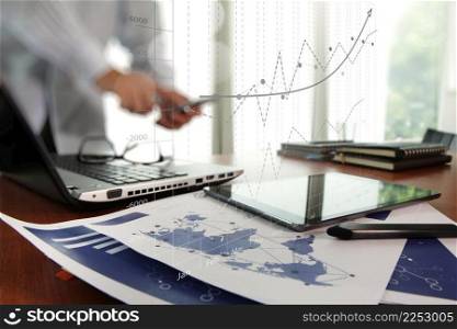 business documents on office table with digital tablet and man working with smart phone in the background with business graph diagram concept 