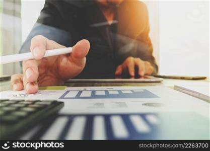 business documents on office table with digital tablet computer with smart phone and graph business diagram and businessman working in the background