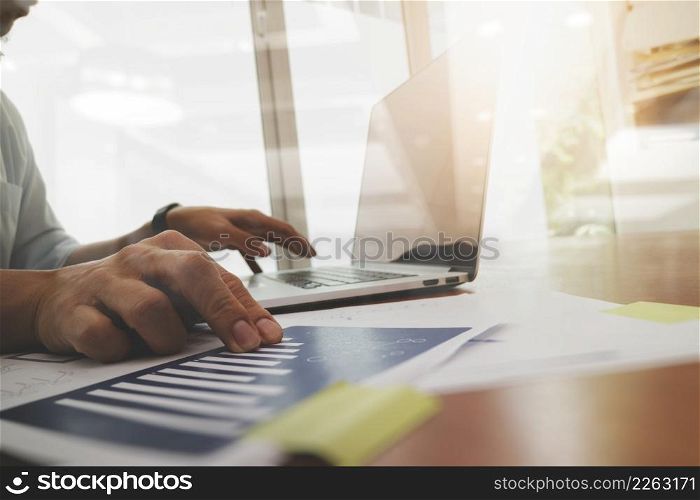 business documents on office table with laptop computer and graph business diagram and man working in the background