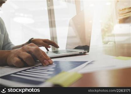 business documents on office table with laptop computer and graph business diagram and man working in the background