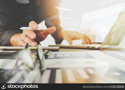 business documents on office table with laptop computer with smart phone and graph business diagram and man working in the background