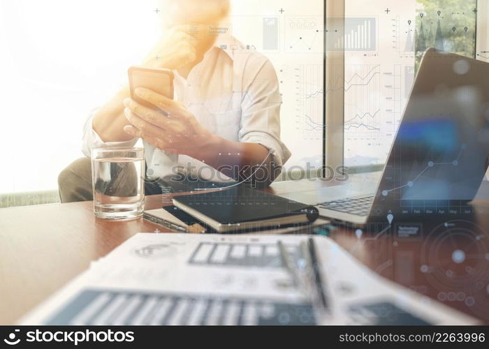 business documents on office table with smart phone and digital laptop computer and graph business diagram and man working in the background