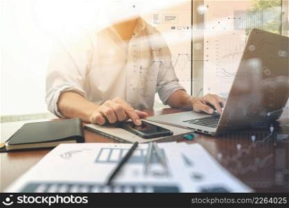 business documents on office table with smart phone and digital laptop computer and graph business diagram and man working in the background