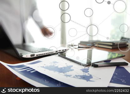 business documents on office table with smart phone and digital tablet and man working in the background