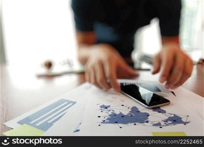 business documents on office table with smart phone and digital tablet and man working in the background
