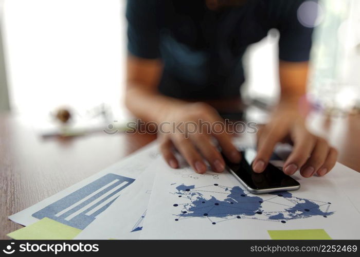 business documents on office table with smart phone and digital tablet and man working in the background