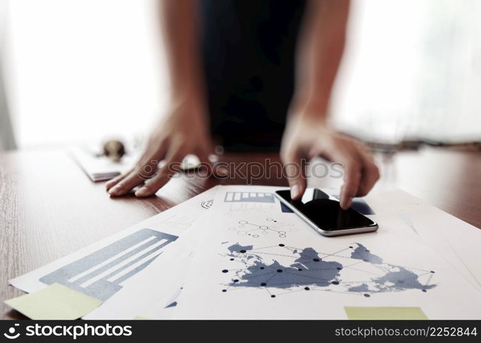 business documents on office table with smart phone and digital tablet and man working in the background