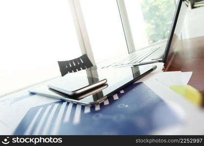 business documents on office table with smart phone and digital tablet and man working in the background