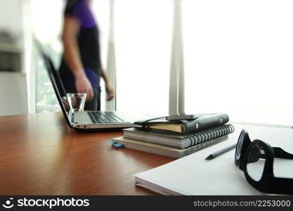 business documents on office table with smart phone and digital tablet and man working in the background