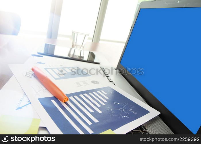 business documents on office table with smart phone and digital tablet and modern pen with blank screen laptop computer in workspace concept