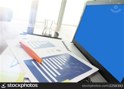 business documents on office table with smart phone and digital tablet and modern pen with blank screen laptop computer in workspace concept