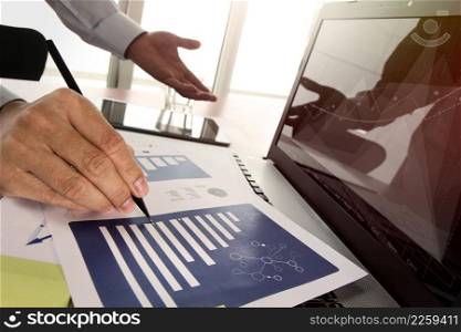 business documents on office table with smart phone and digital tablet and graph business diagram and man working in the background