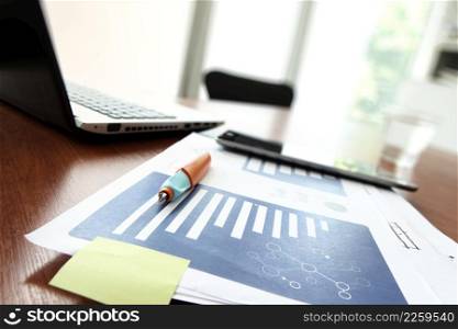 business documents on office table with smart phone and digital tablet and modern pen with laptop computer in workspace concept