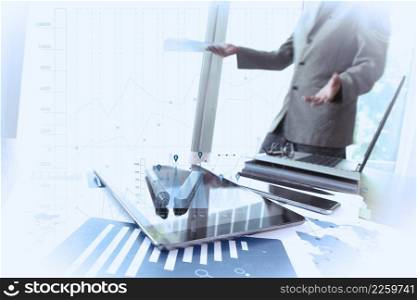 business documents on office table with smart phone and digital tablet and man working in the background with business graph diagram