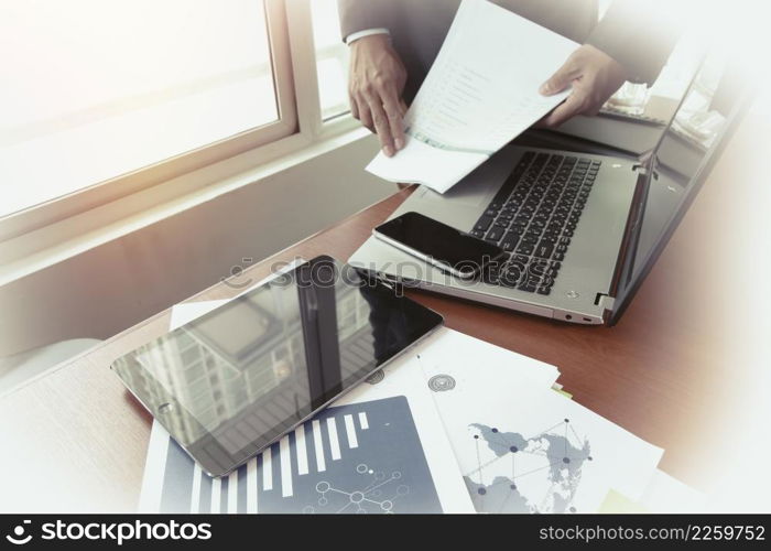 business documents on office table with smart phone and digital tablet and graph business diagram and man working in the background and social media diagram