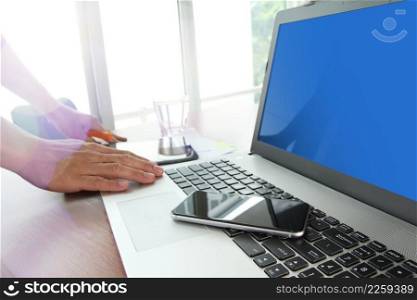 business documents on office table with smart phone and digital tablet with blank screen laptop computer and man working in moment