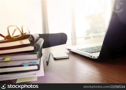 business documents on office table with smart phone and eye glass and modern pen with laptop computer in workspace concept