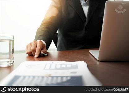 business documents on office table with smart phone and laptop computer and graph business diagram and man working in the background