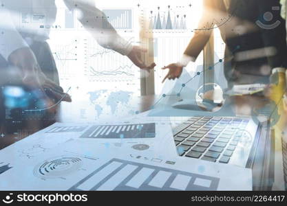 business documents on office table with smart phone and laptop computer and graph business with social network diagram and two colleagues discussing data in the background