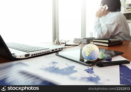 business documents on office table with texture the world on digital tablet and man using smart phone  in the background Elements of this image furnished by NASA