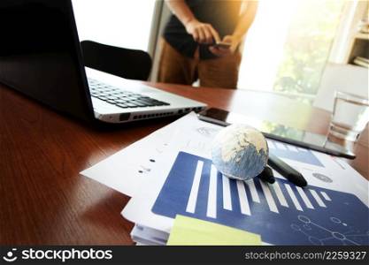 business documents on office table with texture the world on digital tablet and man using smart phone in the background Elements of this image furnished by NASA