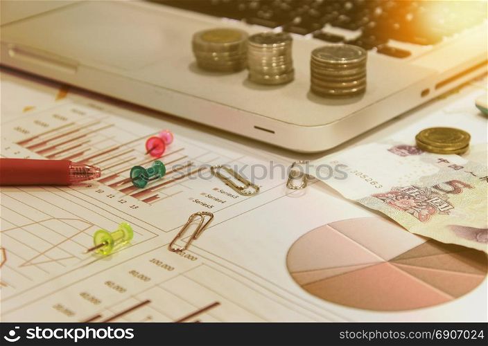 business documents on table with laptop computer and coins and graph financial diagram.