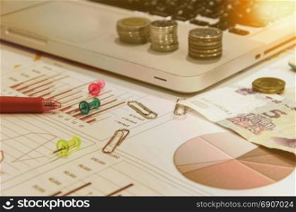 business documents on table with laptop computer and coins and graph financial diagram.