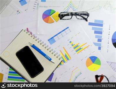 business documents over papers with numbers and charts. View from above