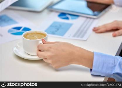 business, drink and people concept - hand of businesswoman drinking coffee at office. hand of businesswoman drinking coffee at office