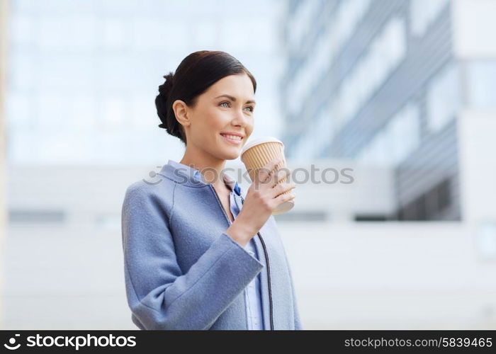 business, drinks, leisure and people concept - smiling woman drinking coffee over office building in city