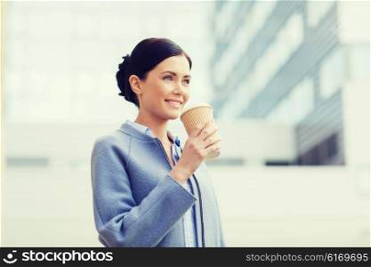 business, drinks, leisure and people concept - smiling woman drinking coffee over office building in city