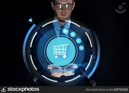business, e-commerce, future technology, cyberspace and people - businessman with virtual shopping cart projection over black background. businessman with virtual shopping cart projection