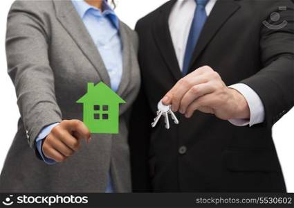 business, eco and real estate concept - businessman and businesswoman holding green house and keys