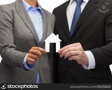 business, eco and real estate concept - businessman and businesswoman holding white paper house