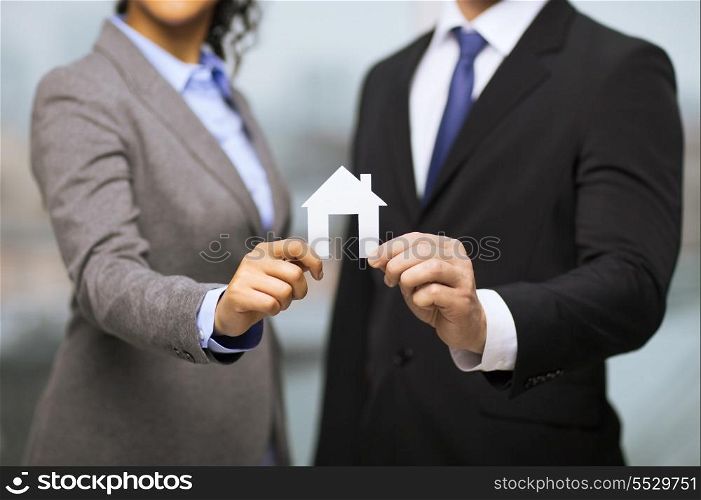 business, eco, real estate and office concept - businessman and businesswoman holding white paper house in office