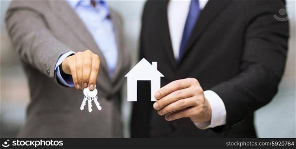 business, eco, real estate and office concept - businessman and businesswoman holding white paper house and keys in office