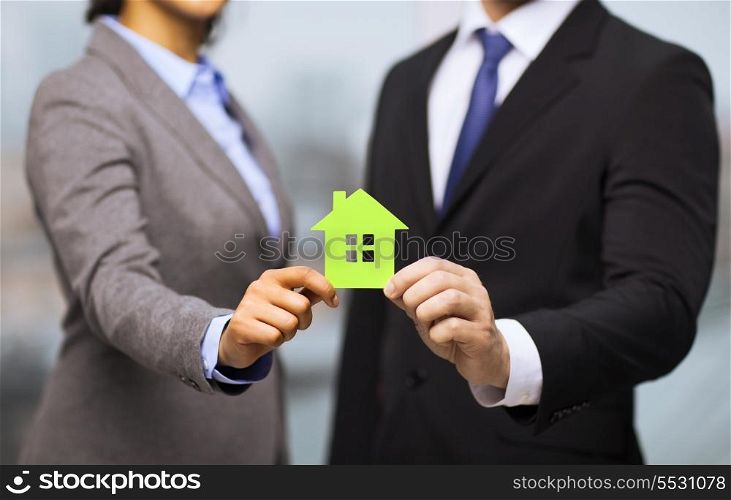 business, eco, real estate and office concept - businessman and businesswoman holding green house in office