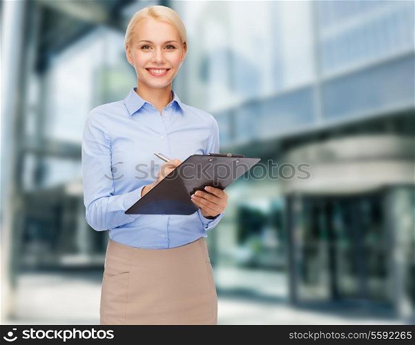 business, education and construction concept - smiling woman writing on a clipboard outdoors in the city center