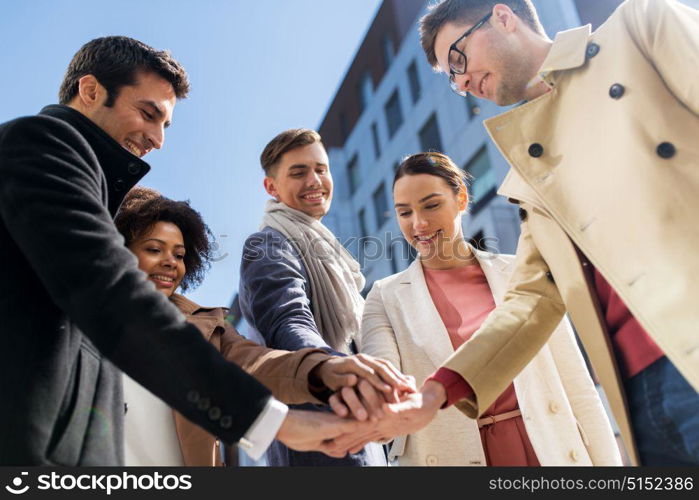 business, education and corporate concept - international group of people holding hands together on city street. group of happy people holding hands in city