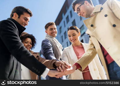 business, education and corporate concept - international group of people holding hands together on city street. group of happy people holding hands in city