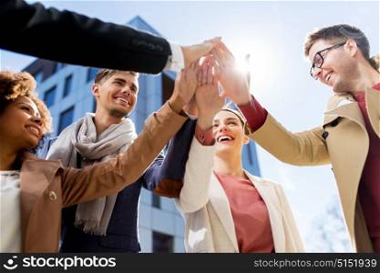 business, education and corporate concept - international group of people or students making high five on city street. group of happy people making high five in city